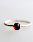 Gold filled minimalist ring featuring a deep red garnet stone, displayed on a white background as handmade January birthstone jewelry.