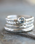 A set of four silver stacking rings with a light london blue topaz gemstone in the center.