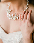 A white pearl necklace with a floral design. The necklace is worn by a person with a gold ring with a small purple stone and clear stones. Morganite Engagement Ring 14k Gold, Princess Cut Morganite Ring