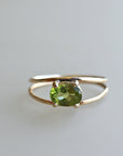 A gold ring with a green oval gemstone set in the center. The ring has a simple design with a thin band. Handmade August Birthstone Ring