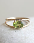 A gold ring with a green oval gemstone. The ring is set with a simple, delicate band.