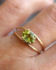 A gold ring with a green oval gemstone set in the center. The ring has a double band design.