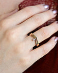 A gold ring with a small diamond set in the center. The ring is designed with two bands that form a V shape.