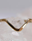 A simple gold ring with a V-shaped design. The ring is made of a smooth, polished metal and has a minimalist aesthetic.
