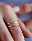 A gold spiral ring with multiple bands. The ring is worn on a finger.