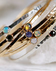 Seven gold and silver hammered stacking open cuff bracelets with various gemstones including opal, garnet, and blue topaz. Birthstone Cuff Bracelets, Gemstone Bracelet, Garnet Bangle, Moonstone Bracelet, Peridot Bracelet, Sterling Silver Cuff Birthstone Jewelry