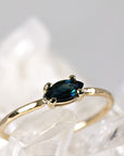 A gold ring with a marquise-shaped blue green sapphire gemstone.