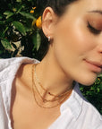 Three gold chain necklaces layered on a person&