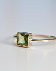 A gold ring with a square green emerald gemstone.