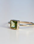 A gold ring with a square green emerald gemstone.