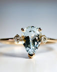 A pear-shaped aquamarine gemstone ring set in gold with two smaller diamond accents.