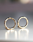 A pair of gold hammered circle stud earrings. The earrings are simple and elegant, and would make a great gift for any occasion.