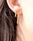 A pair of gold hammered bar earrings. The earrings are simple and elegant, and they would make a great gift for any occasion.