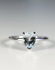 A white gold ring with a pear-shaped aquamarine gemstone.