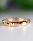 A simple, hammered gold band ring. The ring is a thin band with a textured surface.