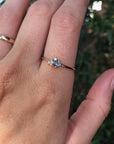 Handmade Family Birthstone Ring in 14k Gold. A delicate gold ring with a small blue gemstone and two smaller white gemstones.