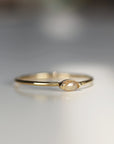A gold band ring with a small, light brown, marquise-shaped diamond