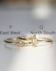 Two gold rings with marquise shaped diamonds. The top ring has the letter &