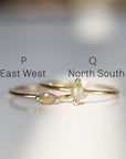 Two gold rings with marquise shaped diamonds. The top ring has the letter &