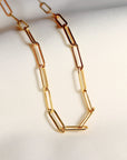 A gold chain necklace with a simple, linked design. The chain is made of small, rectangular links.