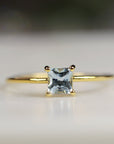 A gold ring with a square-shaped light blue gemstone, aquamarine