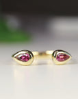 A gold ring with two teardrop-shaped pink tourmaline gemstones set in the band.