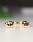 A gold ring with two teardrop-shaped pink tourmaline gemstones set in the band.