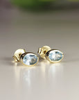 Two gold oval stud earrings with light blue aquamarine gemstones, Bezel Set Aquamarine Stud Earrings,
