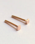 Two small, square-shaped earrings made of rose gold. The earrings are simple and minimalist in design.