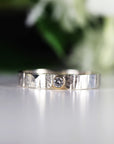A silver band ring with a textured finish and a single, small, round diamond set in a gold bezel.