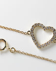 A gold chain bracelet with a heart-shaped charm. The charm is made of small diamonds set in a gold frame. The chain is delicate and has a spring ring clasp closure.