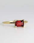 A gold ring with a red rectangular garnet gemstone. The gemstone is set in a simple, minimalist style.