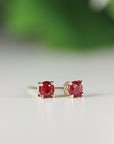 A pair of gold stud earrings with red ruby gemstones.