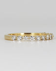 Floating Diamond Wedding Ring. It is Shared Prong Eternity Ring which is Stackable. A gold band with a row of small, round, clear diamonds set in the band.