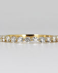 Floating Diamond Wedding Ring. It is Shared Prong Eternity Ring which is Stackable. A gold band with a row of small, round, clear diamonds set in a continuous line around the band.