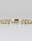 Floating Diamond Wedding Ring. It is Shared Prong Eternity Ring which is Stackable. A gold band with a row of small, round, clear diamonds set in a continuous line around the band.
