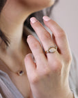 A gold ring with a large oval opal gemstone and smaller diamonds set in a curved band.