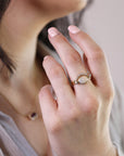 A gold ring with a large oval opal gemstone and smaller diamonds set in a curved band.