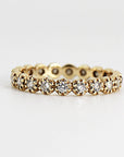A gold band eternity ring with a row of small round diamonds set in a bezel setting.
