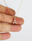 A gold chain necklace with a small gold letter A pendant.