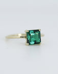 A gold ring with a square emerald green emerald gemstone