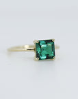 A gold ring with a square emerald green emerald gemstone