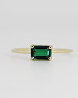 A gold ring with a dark green emerald-cut emerald gemstone.