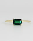 A gold ring with a dark green emerald-cut emerald gemstone.