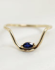 A gold ring with a wave-like design and a single blue sapphire gemstone.