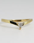 A gold band ring with a triangular diamond in the center. The ring is shaped like a V with the diamond at the point of the V.