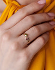 A gold ring with two small gemstones. The top stone is green and the bottom stone is pink.