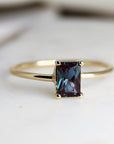A gold ring with a dark blue rectangular modern cut gemstone