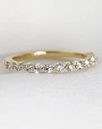 Floating Diamond Wedding Ring. It is Shared Prong Eternity Ring which is Stackable. A gold band with a row of small round diamonds set in the band.