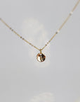 A gold chain necklace with a small, round pendant featuring the letter "A" in a cursive font.
